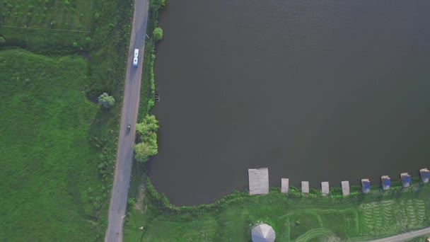 Aereo, drone shot, su camion che guidano su una strada ad alta quota, tra alberi verde chiaro, foresta primaverile, con vista sulle colline e un lago. 4K . — Video Stock