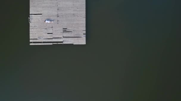 Vlieg over de drone-weergave van een geweldig meisje dat op de pier legt en blij is met de zon. 4k. — Stockvideo