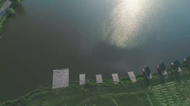 Vista aérea. Lago de agua dulce y sol con muelle y cabañas. 4K . — Vídeos de Stock