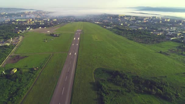 Luftaufnahme von nebligen Bergen und modernen Stadt in flauschigen Wolken, gibt es Flughafen mit Flugzeug, bereit für den Einsatz. 4k. — Stockvideo