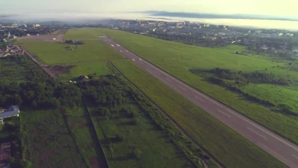 Вид с воздуха на небольшую авиацию, расположенную в непосредственной близости от города с удивительным зданием и природой. 4K . — стоковое видео