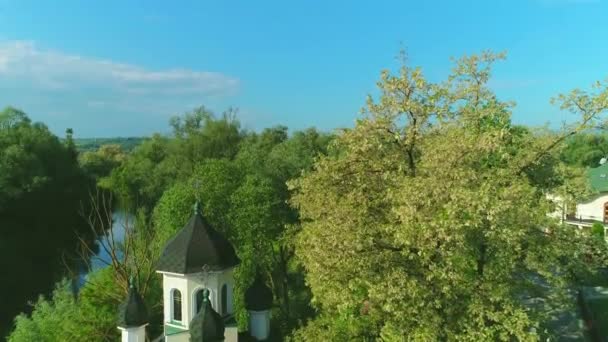 Luchtfoto van de kerk tussen lente boom bloesem en rustige meer. 4k. — Stockvideo