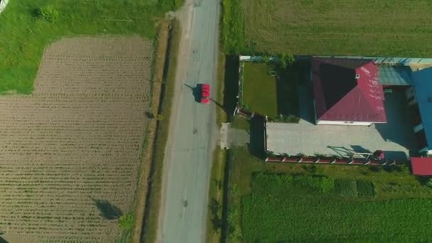 Arriba aérea siguiendo la vista del coche rojo que conduce a lo largo de la carretera. 4K . — Vídeos de Stock