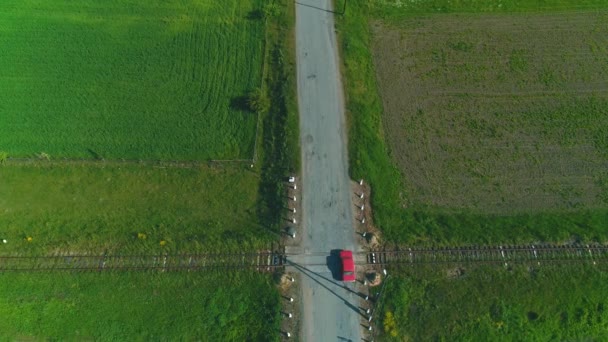 Vue aérienne supérieure suivant la voiture rouge conduisant le long de la route de campagne. 4K .