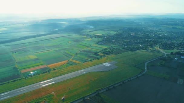 Hög topputsikt över privata flygplan flyttar längs ta av i bygder landningsbana bland gräsmattor. 4K. — Stockvideo