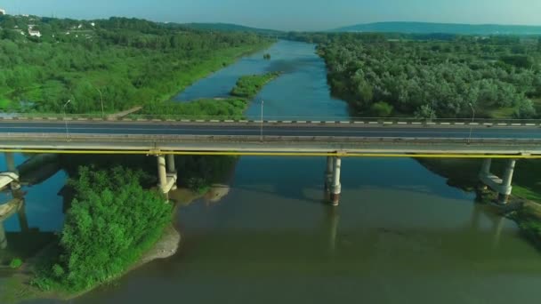 Εναέρια θέα ενός αυτοκινήτου κινείται γρήγορα κατά μήκος γέφυρα δρόμο πάνω από το ήσυχο ποτάμι. 4K. — Αρχείο Βίντεο