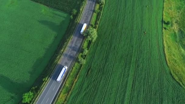 Vol aérien au-dessus des camions conduisant le long de la route entourée de vallées verdoyantes. 4K .