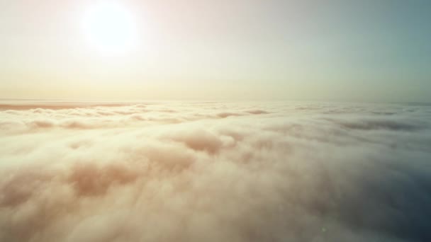 Wysoki widok z lotu ptaka na duże błyszczące słońce nad puszystymi złotymi chmurami. 4K. — Wideo stockowe