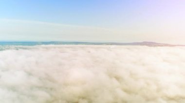 4k geniş çekim kabarık beyaz bulutlar gibi mavi bir gökyüzünde parlayan güneşe bakarak.