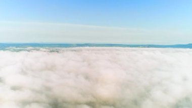 Yoğun kabarık bulutlardan gün batımında şehrin havai manzarasına doğru havadan görünüm.