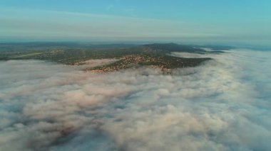 Yoğun kabarık bulutlardan gün batımında şehrin havai manzarasına doğru havadan görünüm.