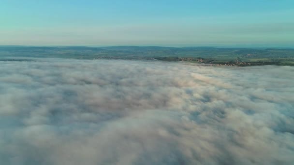 Vista aérea que se aproxima desde densas nubes esponjosas a la vista aérea de la ciudad al atardecer . — Vídeos de Stock