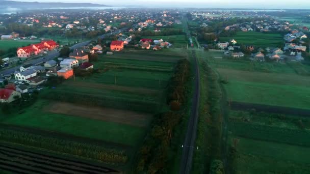 Un dron vuela sobre un ferrocarril cerca de casas con mucha vegetación alrededor. 4K — Vídeo de stock