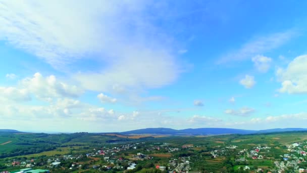 Ett flygfoto över en charmig liten by mitt bland ängar, skog och bergens siluett. 4k — Stockvideo