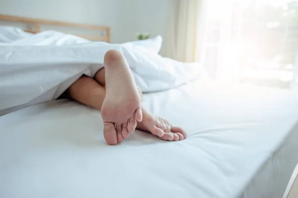 若い女性が足に焦点を当てて自宅でベッドで寝ています ベッドに寝そべっている女の足 — ストック写真
