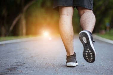 Sabah koşusundan başlayarak. Spor kıyafetleriyle parkta koşan genç bir adam. Gün batımında dışarıda koşuya hazır.