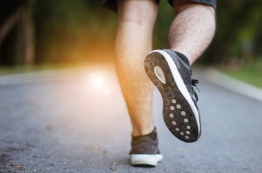 Sabah koşusundan başlayarak. Spor kıyafetleriyle parkta koşan genç bir adam. Gün batımında dışarıda koşuya hazır.