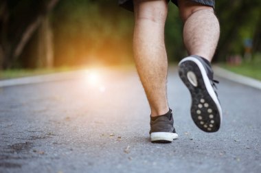 Sabah koşusundan başlayarak. Spor kıyafetleriyle parkta koşan genç bir adam. Gün batımında dışarıda koşuya hazır.