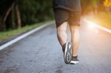 Sabah koşusundan başlayarak. Spor kıyafetleriyle parkta koşan genç bir adam. Gün batımında dışarıda koşuya hazır.