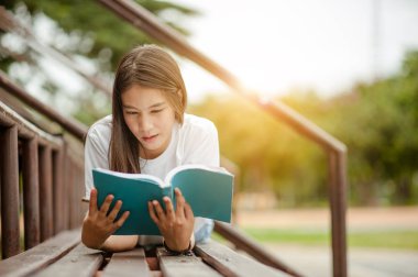 Amfitiyatroda elinde bir kitapla uzanan güzel esmer kadın. Romantik açık hava kavramı.