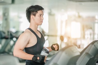 Spor giyimli genç adam spor salonunda koşu bandında koşuyor. Spor, spor, spor, yaşam tarzı, teknoloji ve insan konsepti. Spor salonunda koşu bandında egzersiz yapan gülümseyen adamlar..