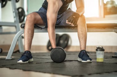 Vücut geliştirici, spor salonunda halter ağırlıklarıyla çalışıyor. Yakışıklı atletik erkek vücut geliştirici, halterle egzersiz yapıyor. Fitness kaslı vücut 