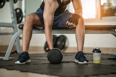 Vücut geliştirici, spor salonunda halter ağırlıklarıyla çalışıyor. Yakışıklı atletik erkek vücut geliştirici, halterle egzersiz yapıyor. Fitness kaslı vücut 