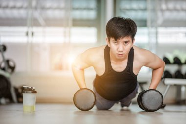 Spor. Spor salonunda tek elle şınav çeken yakışıklı bir adam. Spor salonunda beden eğitimi hocası - Zihnini kontrol et, vücudunu fethet. Yakışıklı kaslı adam spor salonunda dambıllarla çalışıyor.