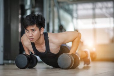 Spor. Spor salonunda tek elle şınav çeken yakışıklı bir adam. Spor salonunda beden eğitimi hocası - Zihnini kontrol et, vücudunu fethet. Yakışıklı kaslı adam spor salonunda dambıllarla çalışıyor.