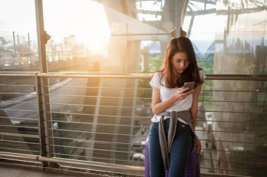 Kadınlar havaalanlarındaki uçuş kontrollerinde akıllı telefonlarını kullanıyorlar. Havaalanları ve teknoloji konsepti
