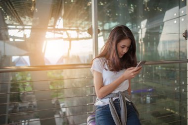 Kadınlar havaalanlarındaki uçuş kontrollerinde akıllı telefonlarını kullanıyorlar. Havaalanları ve teknoloji konsepti