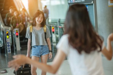 Asyalı kız abroaddan arkadaşlarını kucaklayacak. Havaalanı konsepti. Havaalanları kucaklaşması..