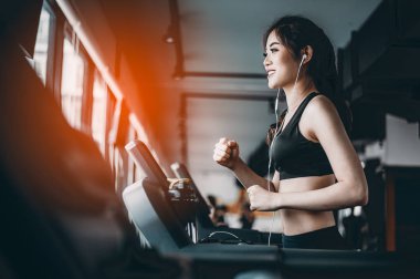 Spor salonunda koşu bandında koşan kadın portresi müzik dinliyor.Egzersiz konsepti. Fitness ve sağlıklı yaşam tarzı..