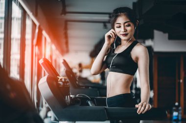 Spor salonunda koşu bandında koşan kadın portresi müzik dinliyor.Egzersiz konsepti. Fitness ve sağlıklı yaşam tarzı..