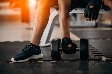 Vücut geliştirici, spor salonundaki halter ağırlıklarıyla çalışıyor. Halterle egzersiz yapıyor. Fitness kaslı vücut 