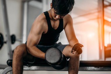 Vücut geliştirici, spor salonundaki halter ağırlıklarıyla çalışıyor. Halterle egzersiz yapıyor. Fitness kaslı vücut 