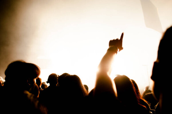 silhouettes of hand in concert.Light from the stage.