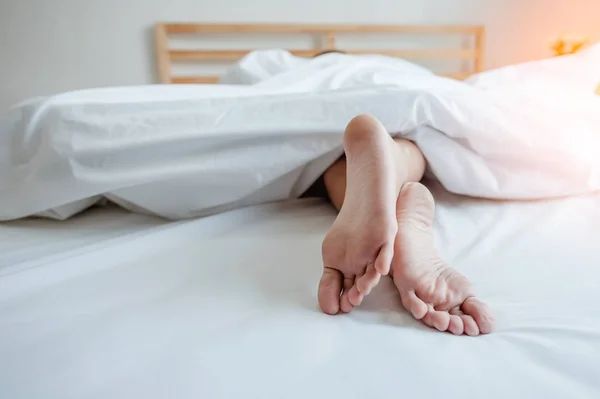 若い女性が足に焦点を当てて自宅でベッドで寝ています ベッドに寝そべっている女の足 — ストック写真