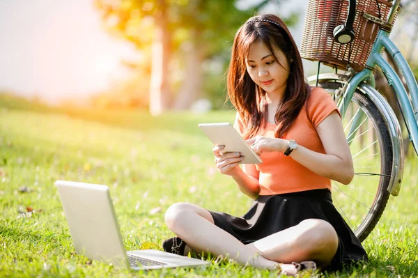 年轻美丽的亚洲女人在室外公园用笔记本电脑 互联网 网上购物 — 图库照片