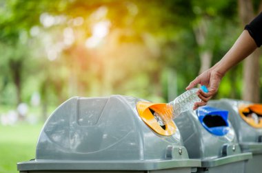 Seçici odak elin boş plastik şişeyi çöpe atıyor.