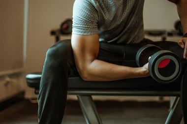 Vücut geliştirici, spor salonundaki halter ağırlıklarıyla çalışıyor. Halterle egzersiz yapıyor. Fitness kaslı vücut 