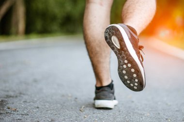 Sabah koşusundan başlayarak. Spor kıyafetleriyle parkta koşan genç bir adam. Gün batımında dışarıda koşuya hazır.