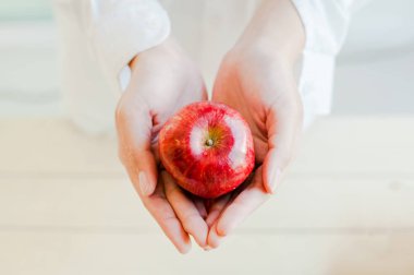 Kırmızı elma tutan genç bir kadının elleri. Sağlıklı yiyecekler, üst manzara.
