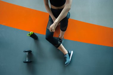 Eğitimden sonra dinleniyorum. Spor salonunda halter ve protein şişesiyle oturan genç bir kadın. Spor salonunda genç bir bayan..
