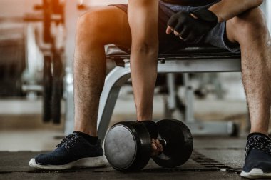 Vücut geliştirici, spor salonundaki halter ağırlıklarıyla çalışıyor. Halterle egzersiz yapıyor. Fitness kaslı vücut 