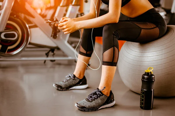 Spor salonunda müzik dinleyen fitness kadınının portresi. Egzersiz konsepti. Fitness ve sağlıklı yaşam tarzı. 