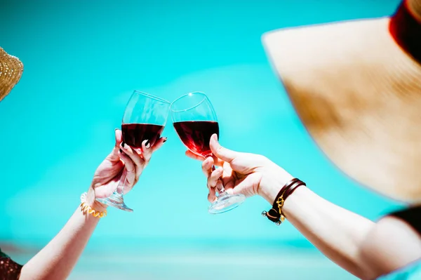 People holding glasses of red wine .wine at a relax party celebration gathering at the beach.Sumer.wine beach two girl.Minimal Summer holidays.