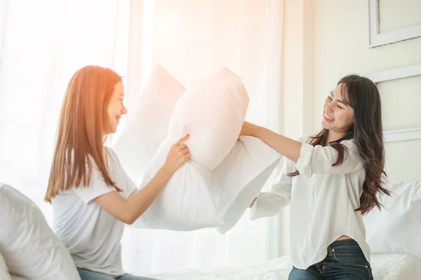 lesbian women at pillow fights in bedroom.