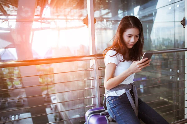 女孩们一起在机场使用智能手机检查航班或网上报到 还带着行李 航空旅行 暑假或手机申请 — 图库照片