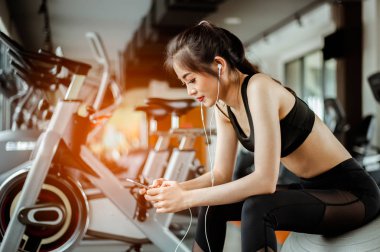 Spor salonunda müzik dinleyen fitness kadınının portresi. Egzersiz konsepti. Fitness ve sağlıklı yaşam tarzı. 